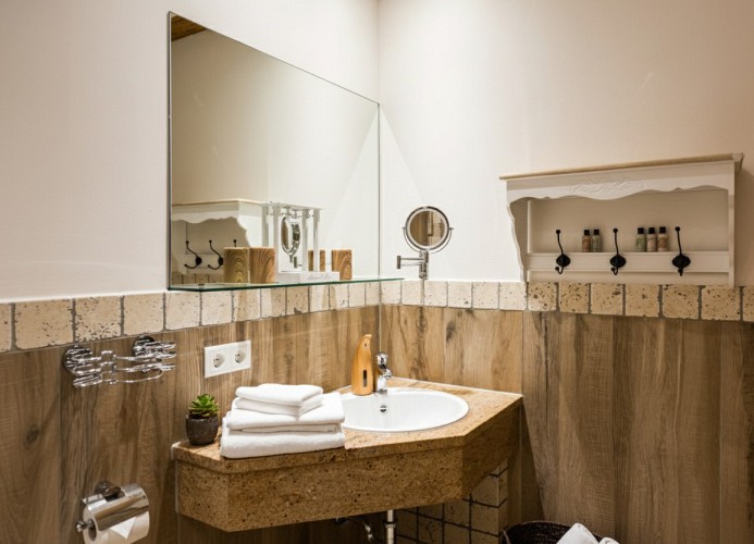 „Stilvoller Waschbereich: Hochwertiges Design mit Granit-Waschtisch und liebevollen Details in Holzoptik.“