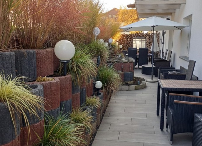 Blühende Gartenarchitektur: Die Terrassengestaltung mit modernen Pflanzsteinen und stimmungsvollen Kugelleuchten